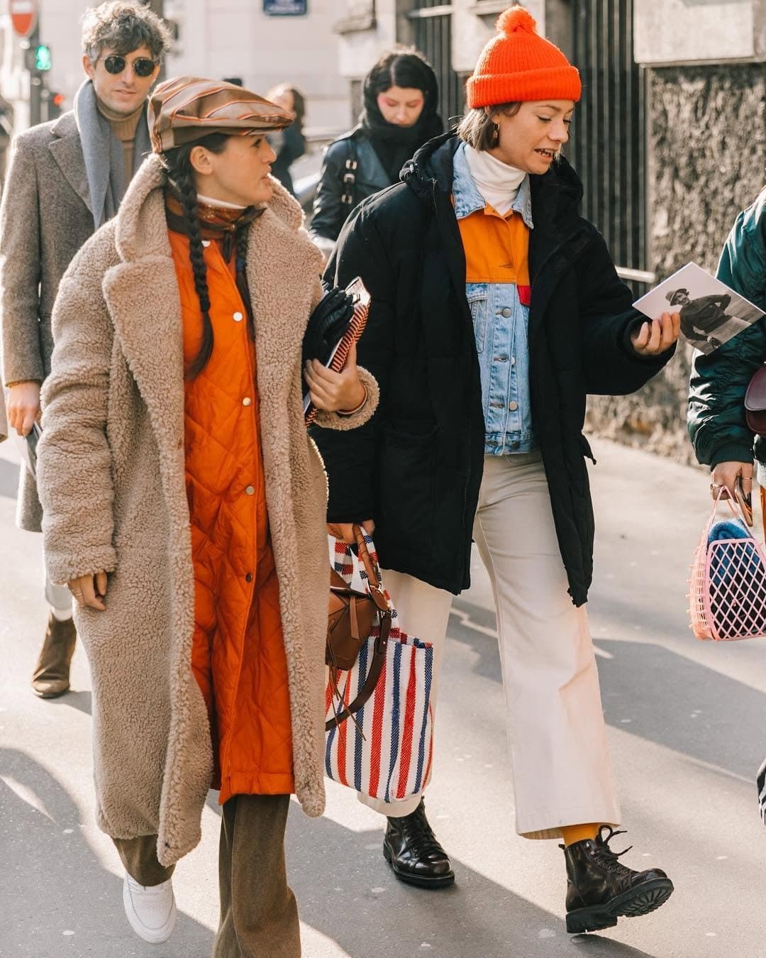 Two layered winter street-style looks mix plush outerwear, bright orange accents, denim, cropped trousers, and chunky footwear.